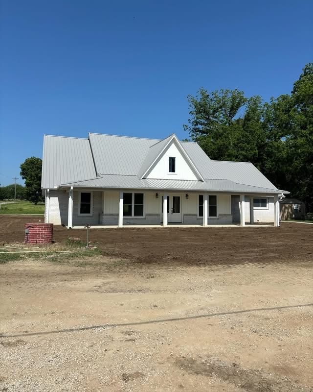 White farmhouse-style custom home with metal roof and front porch