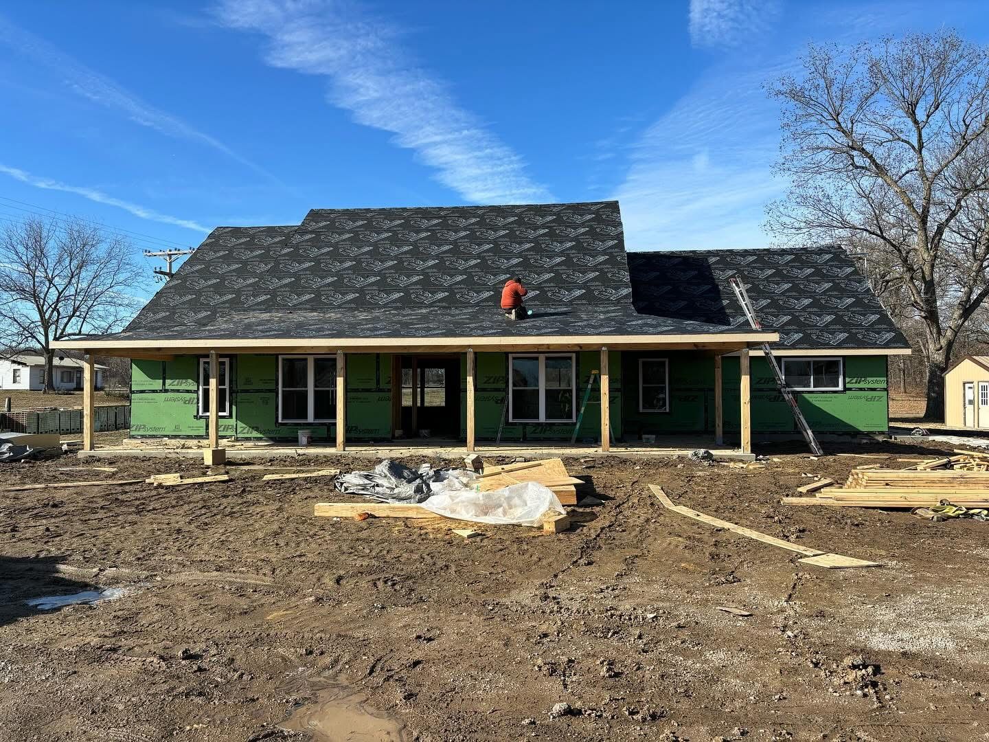 New home under construction with roof shingles going on