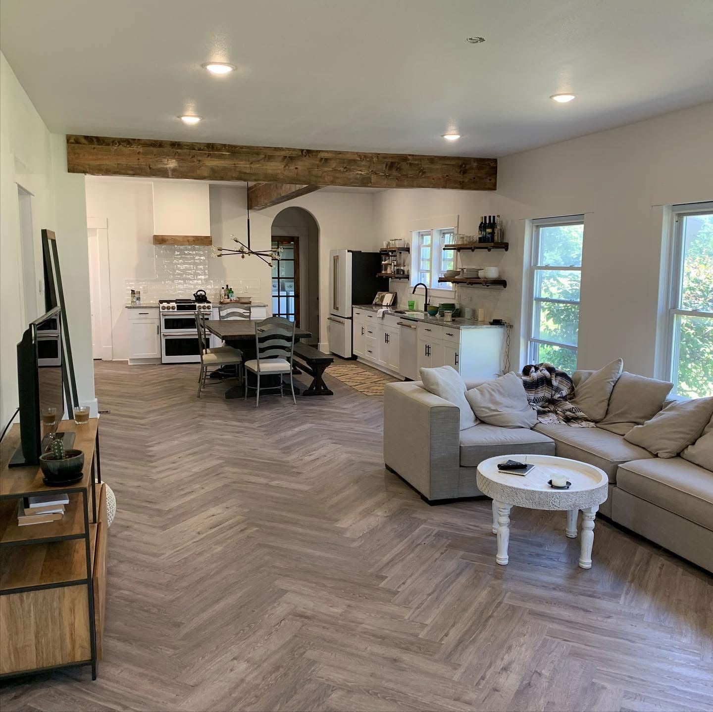 Remodeled open kitchen and living room with herringbone floor and a wood ceiling beam