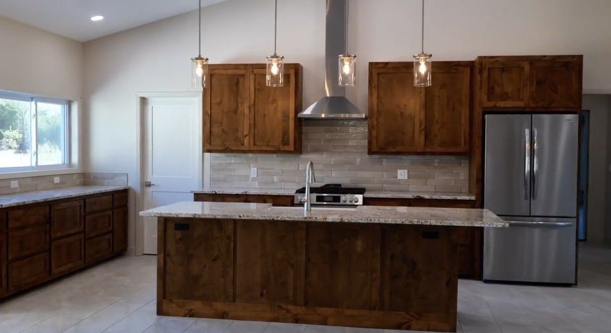Kitchen with knotty alder cabinets, granite island and pendant lights