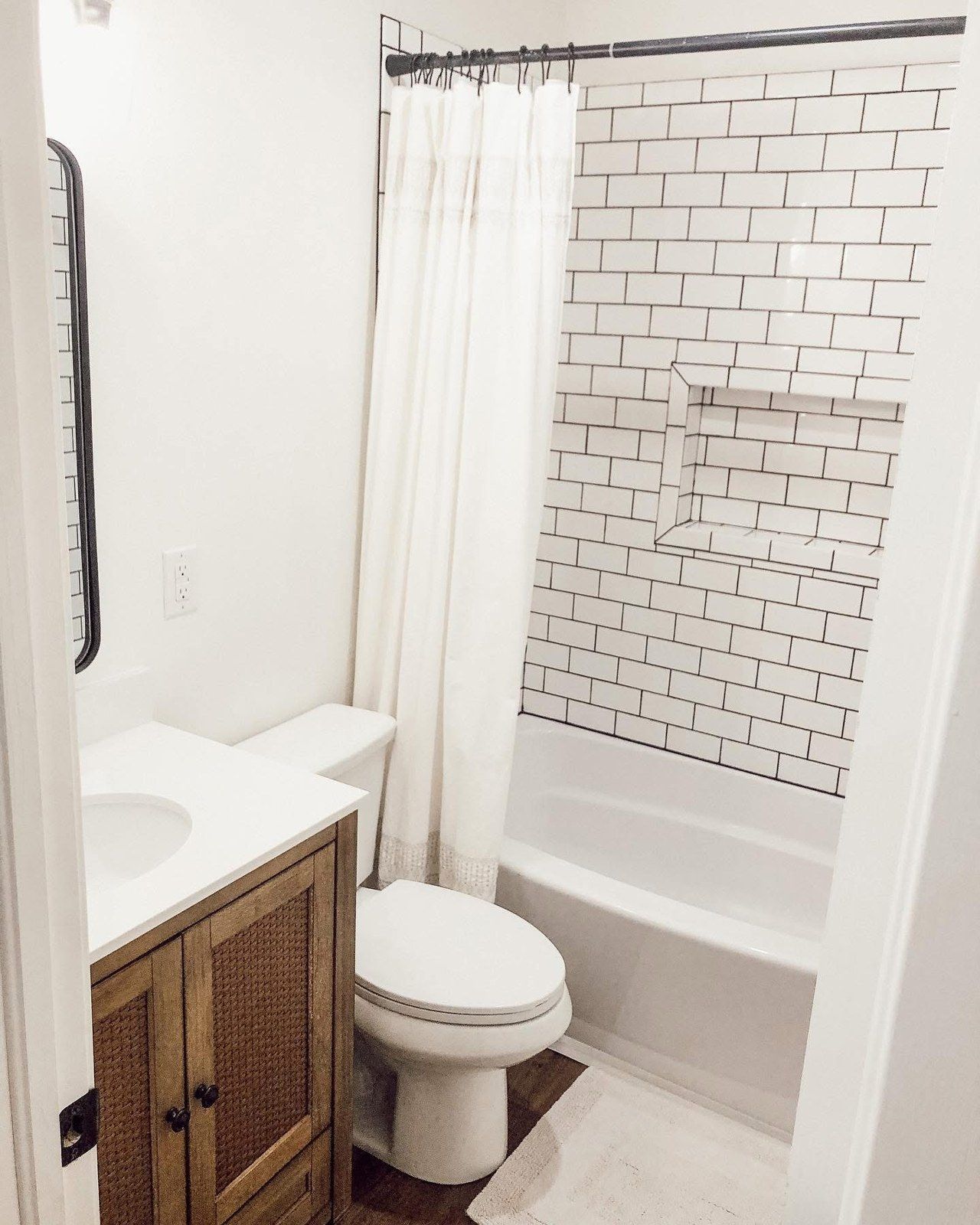 Remodeled bathroom with white subway tile and wood vanity