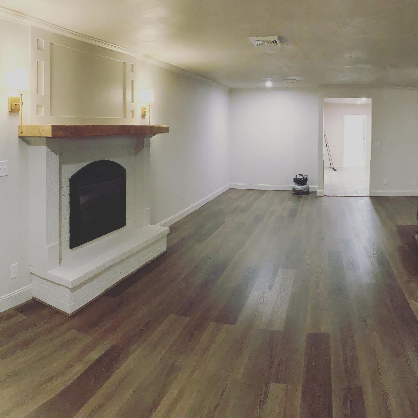 Living room after remodel with painted fireplace, wood mantel and new flooring