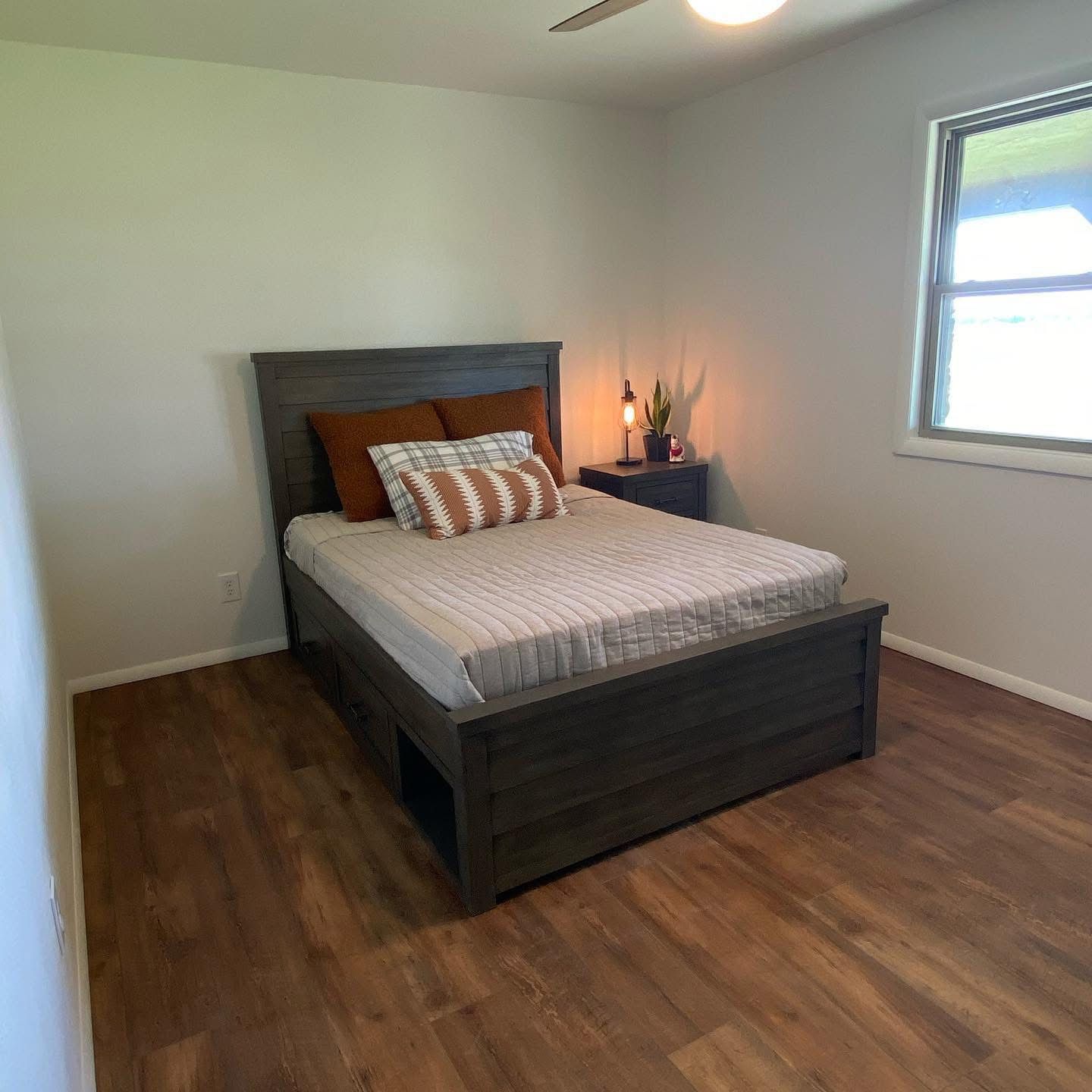 Bedroom after remodel with fresh drywall, paint and wood-look flooring